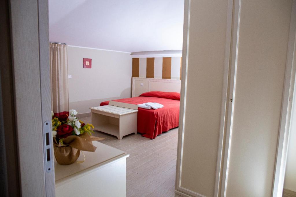 una camera con un letto con copriletto rosso di Hotel Al Rustico a Crosia