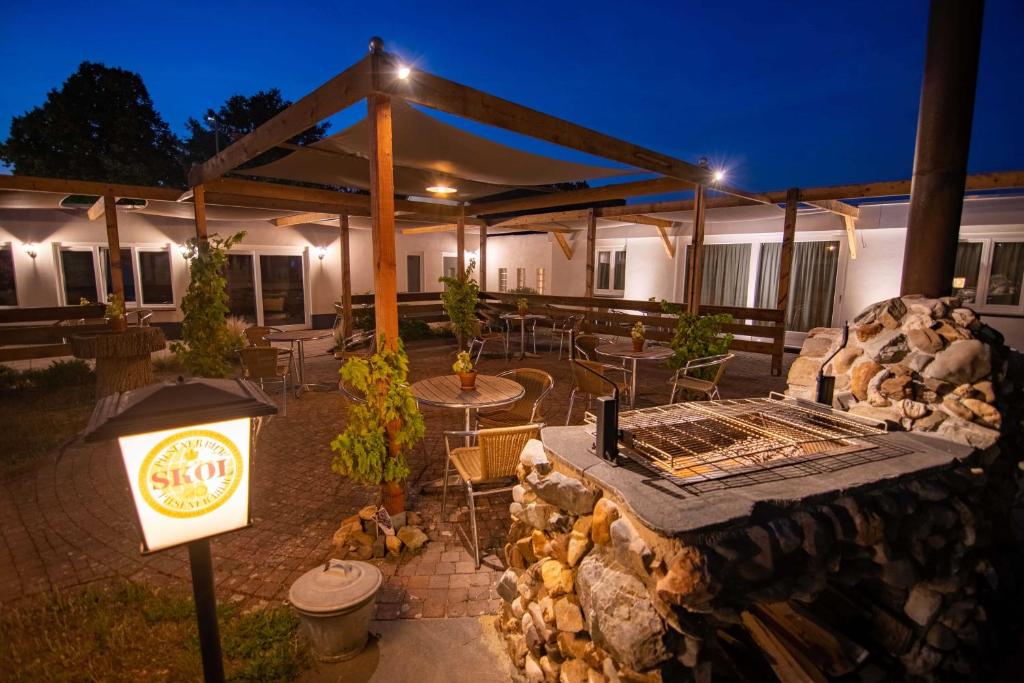 un patio al aire libre con parrilla, mesas y sillas en B&B Katoo, en Linne