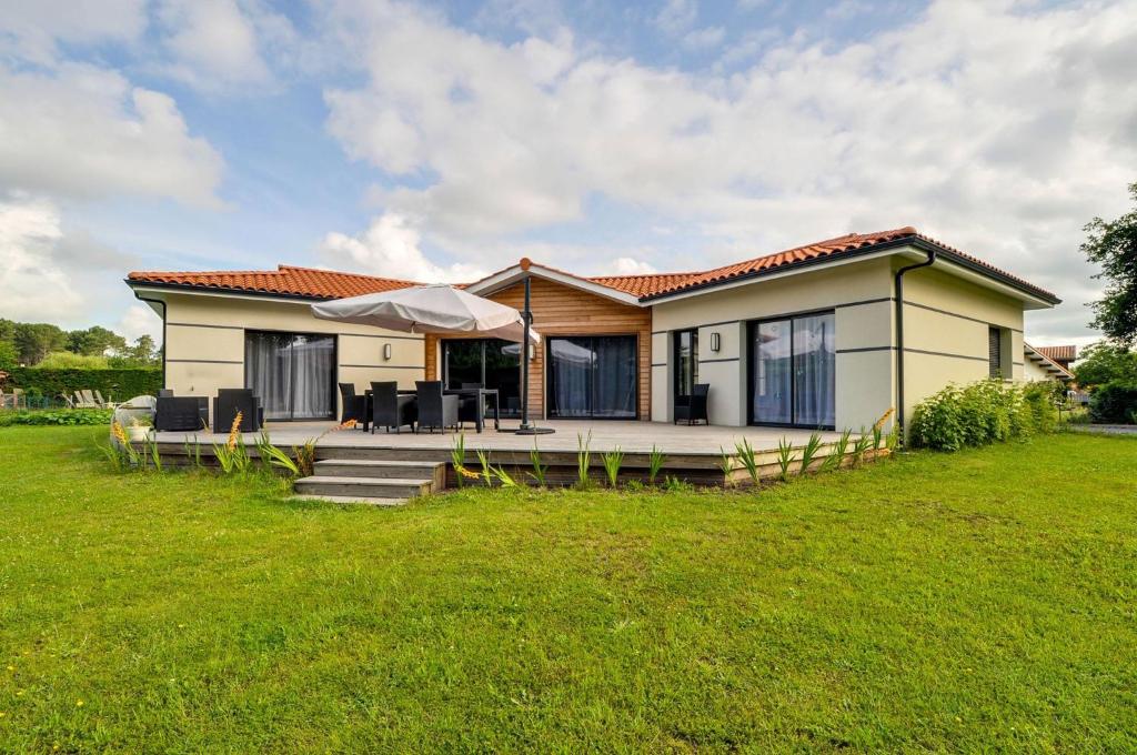 uma pequena casa com um relvado verde em frente em BISCADODO, joignable au zéro6trente53cinquante60 em Biscarrosse