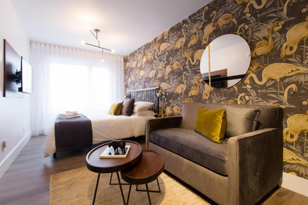 a bedroom with a bed and a couch and a mirror at Fun & Funky Little Italy Studio with Full Kitchen by Den Stays in Montréal