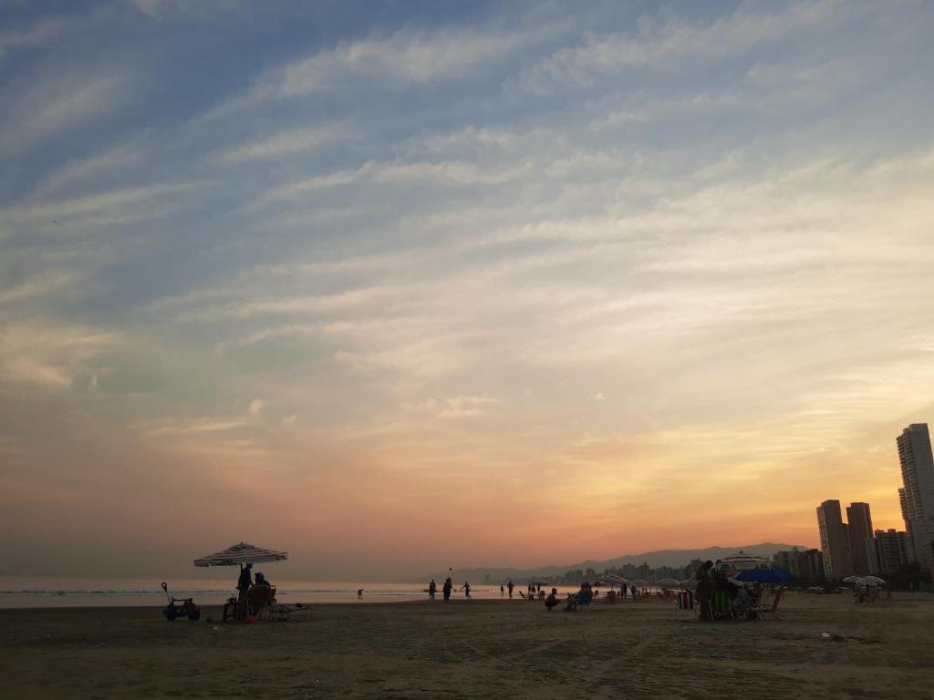 a group of people on the beach at sunset at Apartamento Boqueirao in Praia Grande