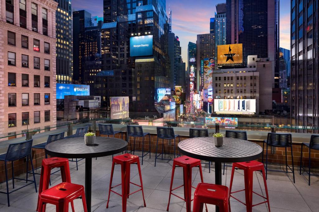 two tables and red stools on a rooftop with a city skyline at M Social Hotel Times Square New York in New York