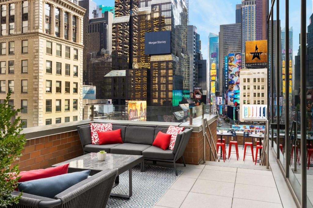 a balcony with couches and tables and a city at M Social Hotel Times Square New York in New York