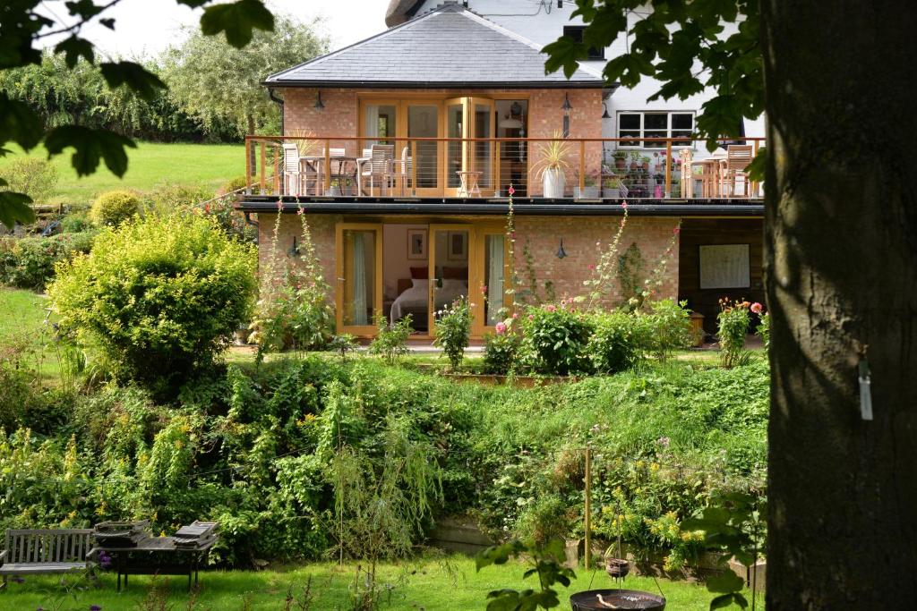 a brick house with a balcony in a garden at Thatchcombe B&B in Wantage
