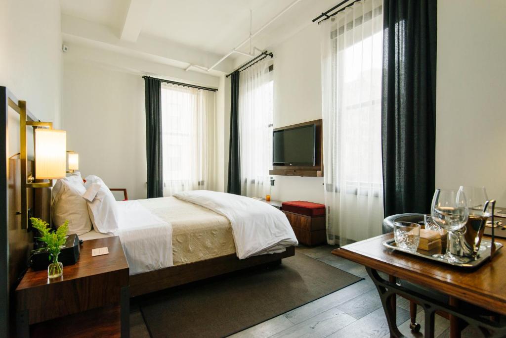 a hotel room with a bed and a television at Refinery Hotel - New York in New York