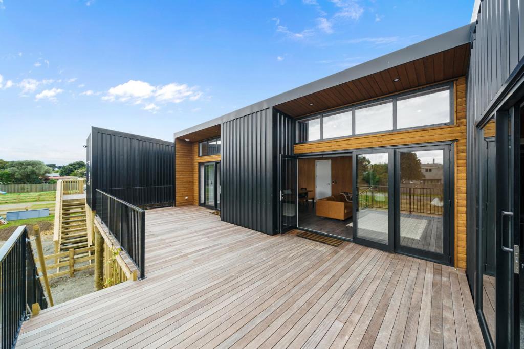 a house with a large deck with glass doors at Kapiti Heights - Ōtaki Beach Holiday Home in Otaki Beach