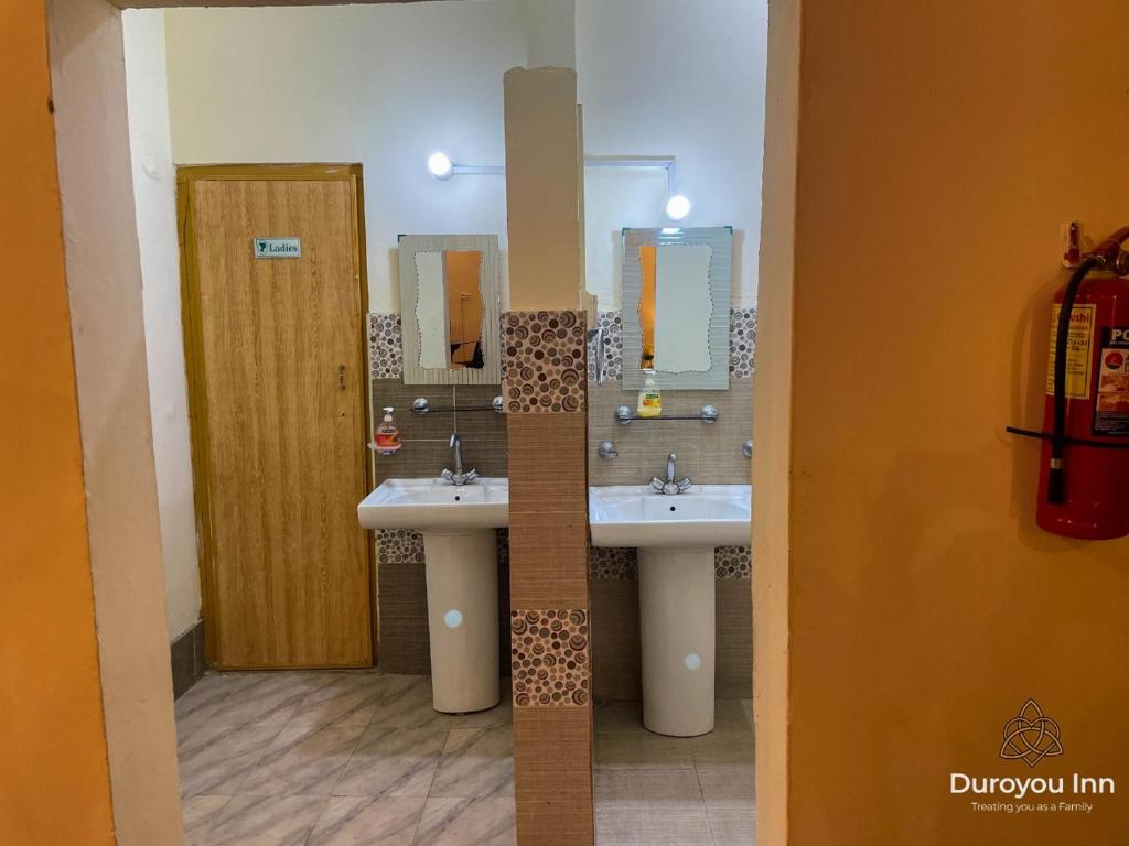 La salle de bains est pourvue de 2 lavabos et de 2 miroirs. dans l'établissement Duroyou Inn, à Gilgit