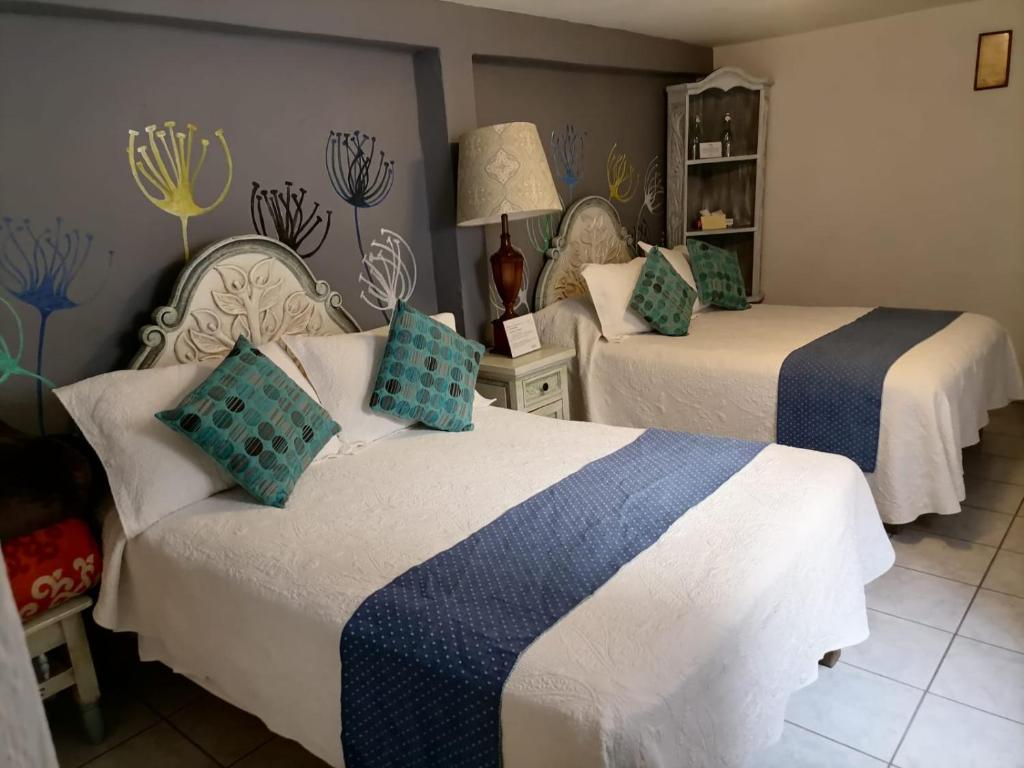 a bedroom with two beds with blue and white sheets at Hotel Santa Ana in San Miguel de Allende