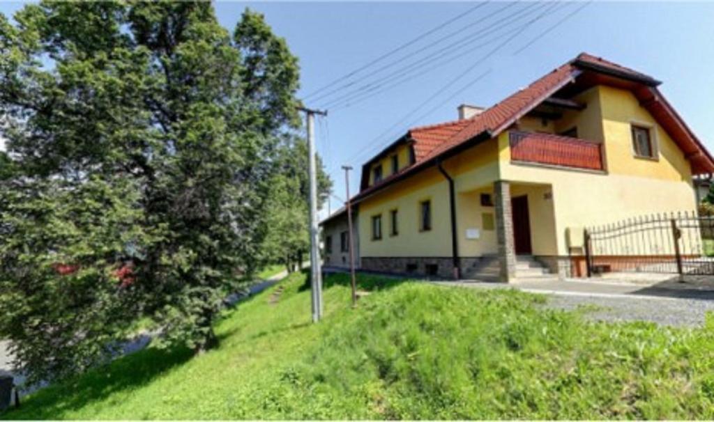una casa amarilla en una colina junto a un árbol en Vila Strážan en Poprad