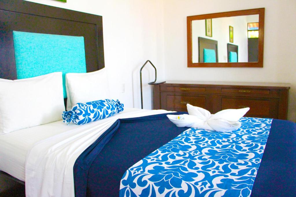 Un dormitorio con una cama azul y blanca con espejo en Hotel Ameyali Tequesquitengo, en Tequesquitengo