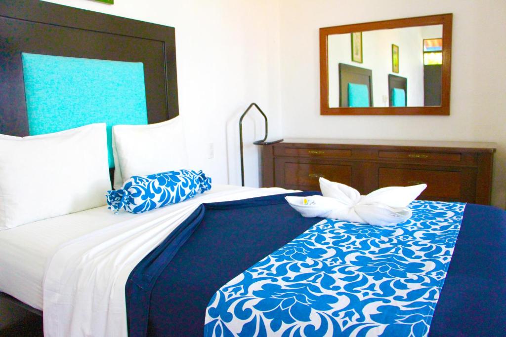 a bedroom with a blue and white bed with a mirror at Hotel Ameyali Tequesquitengo in Tequesquitengo