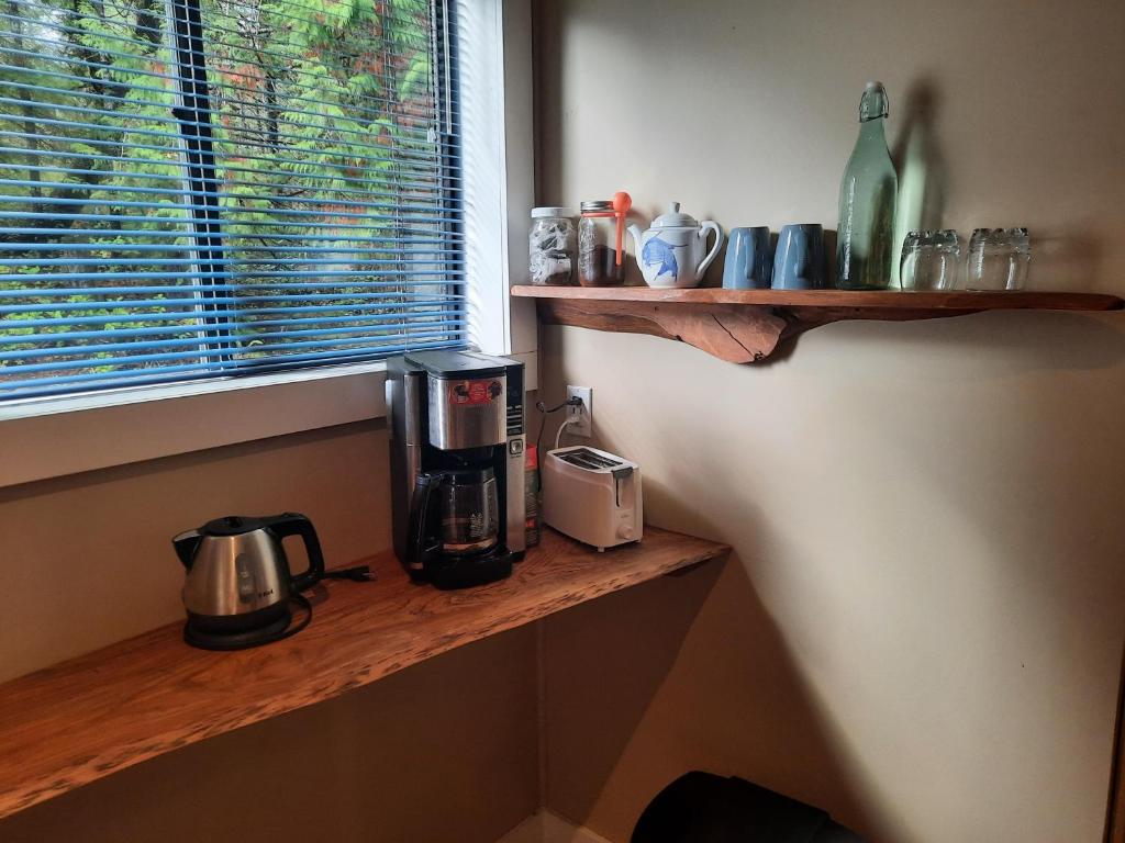 a coffee maker on a wooden shelf next to a window at Beaver Hut Bed And Breakfast in Port Alberni