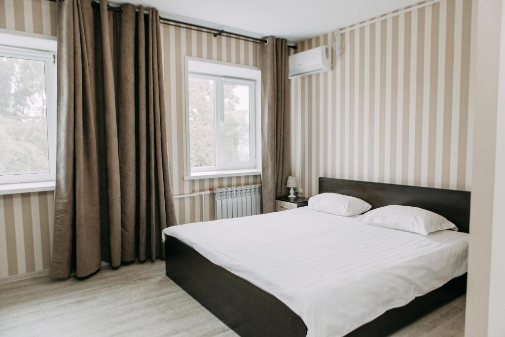 a bedroom with a large bed and two windows at Золотая Ригма in Khabarovsk
