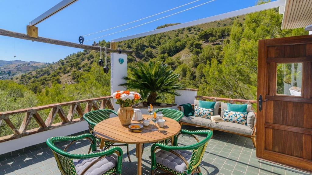 patio ze stołem i krzesłami na balkonie w obiekcie Finca Colores en el Viento Frigiliana by Ruralidays w mieście Frigiliana