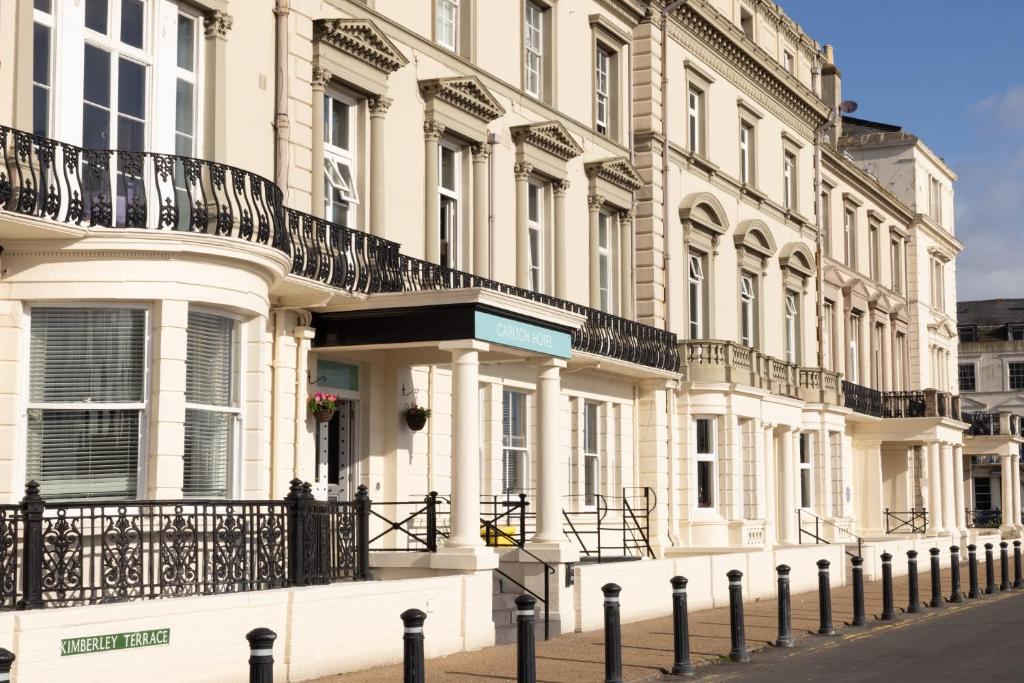 un grand bâtiment blanc avec une clôture devant lui dans l'établissement The Carlton Hotel, à Great Yarmouth