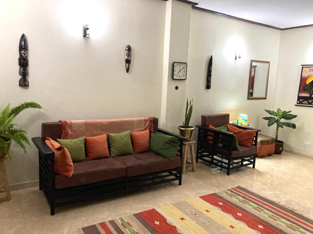 uma sala de estar com um sofá e duas cadeiras em OKRA HOUSE em Entebbe