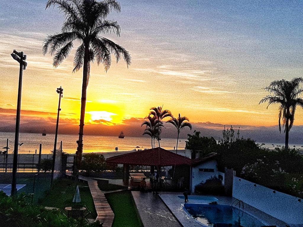 a sunset at a resort with palm trees and a pool at Residencial Privilegio in Florianópolis