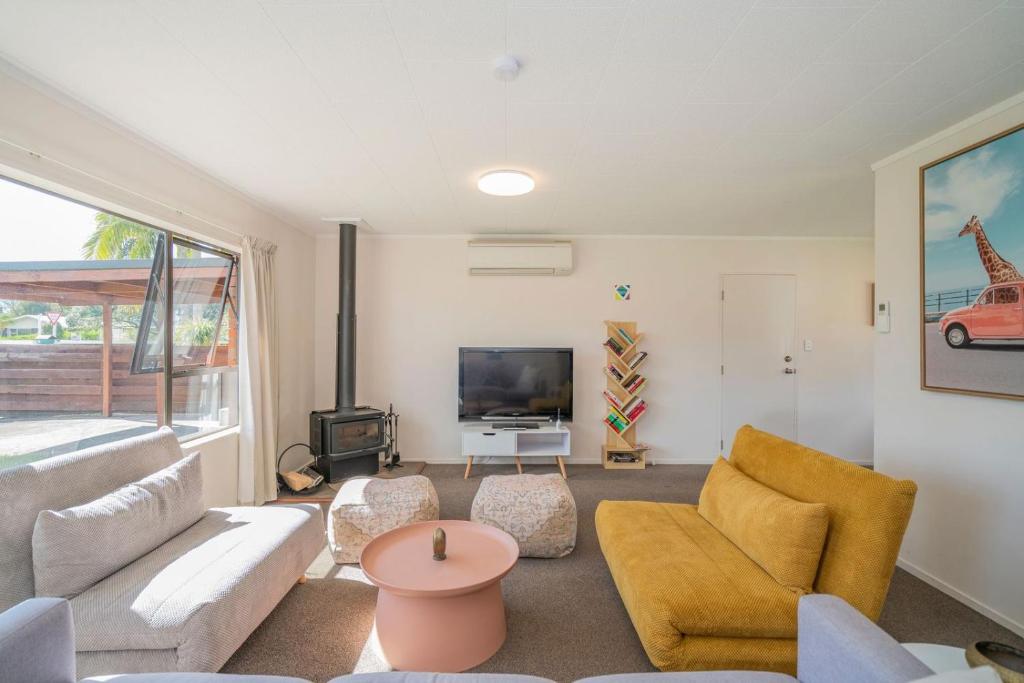 a living room with a couch and a tv at Hosts on the Coast Cosy on Cath in Whitianga