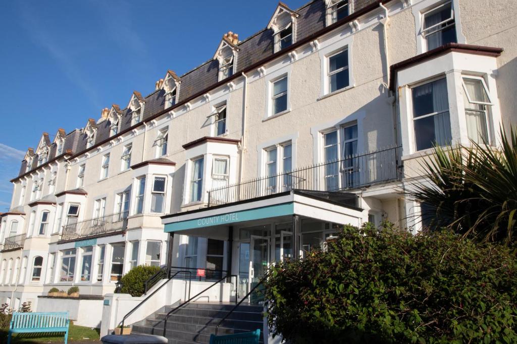 a large white building with a staircase in front of it at The County Hotel in Llandudno