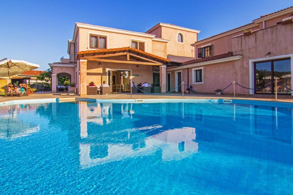 a large swimming pool in front of a house at Hotel La Perla in Àrbatax