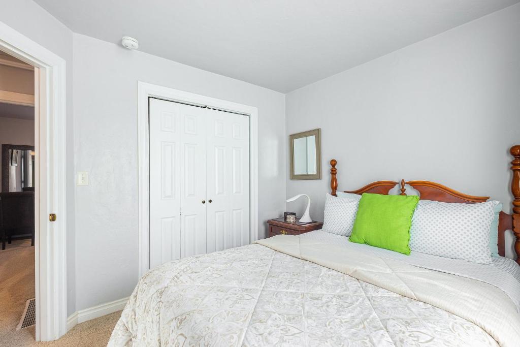 a white bedroom with a bed with a green pillow at Duplex in Alberta Art District in Portland