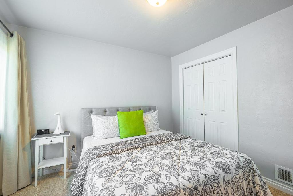 a white bedroom with a bed with a green pillow at Duplex in Alberta Art District in Portland