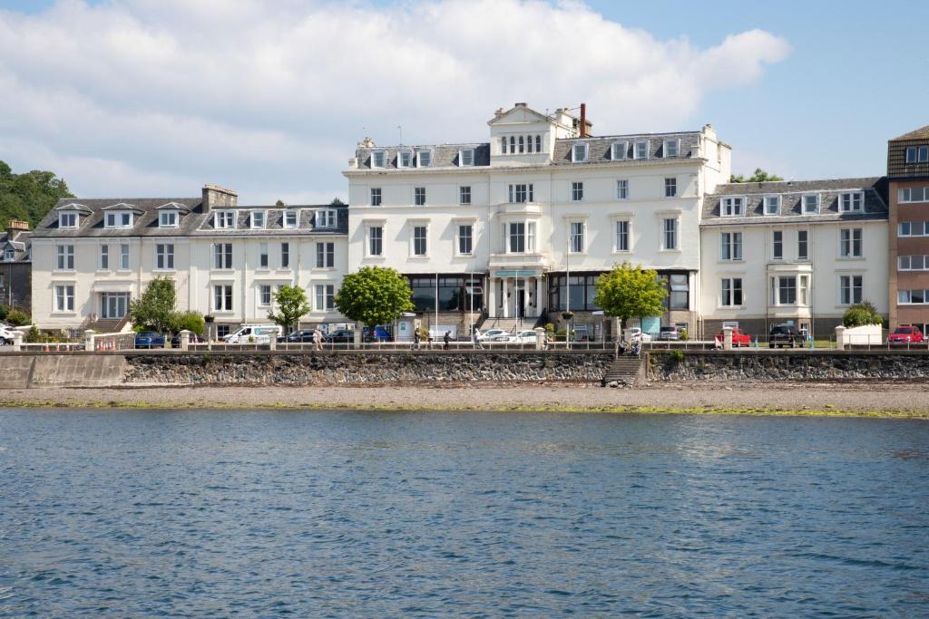 una fila de edificios blancos junto a un cuerpo de agua en The Great Western Hotel en Oban