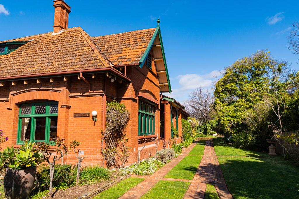 a brick house with a green window and a yard at Buxton Manor in Adelaide