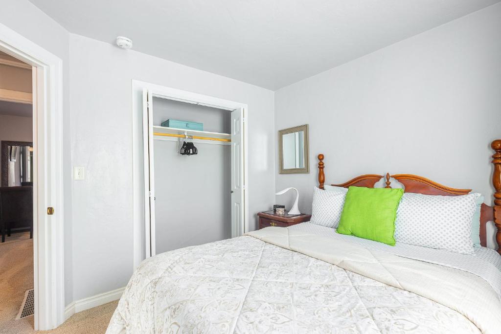 a white bedroom with a bed with a green pillow at Duplex in Alberta Art District in Portland
