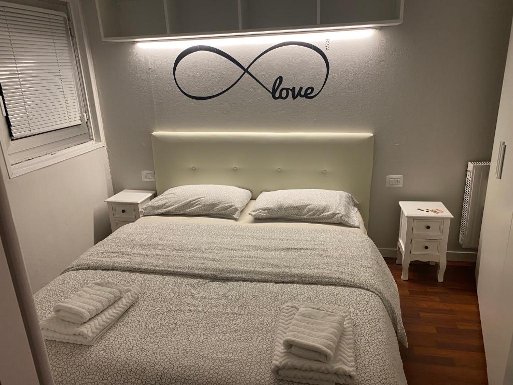 ein Schlafzimmer mit einem Bett mit einem Liebesschild darüber in der Unterkunft Luna Bianca Apartment in Vermiglio