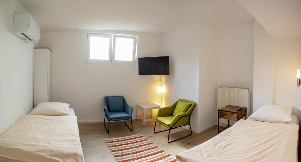 a room with two beds and a chair and a tv at Lauers Ferienwohnung 2 in Schoneck