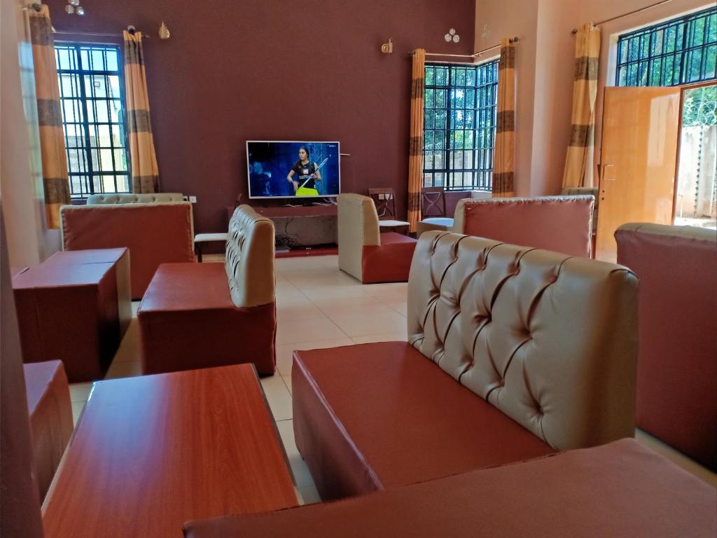 a waiting room with tables and chairs and a tv at The Peak Meadows Hotel in Nyeri
