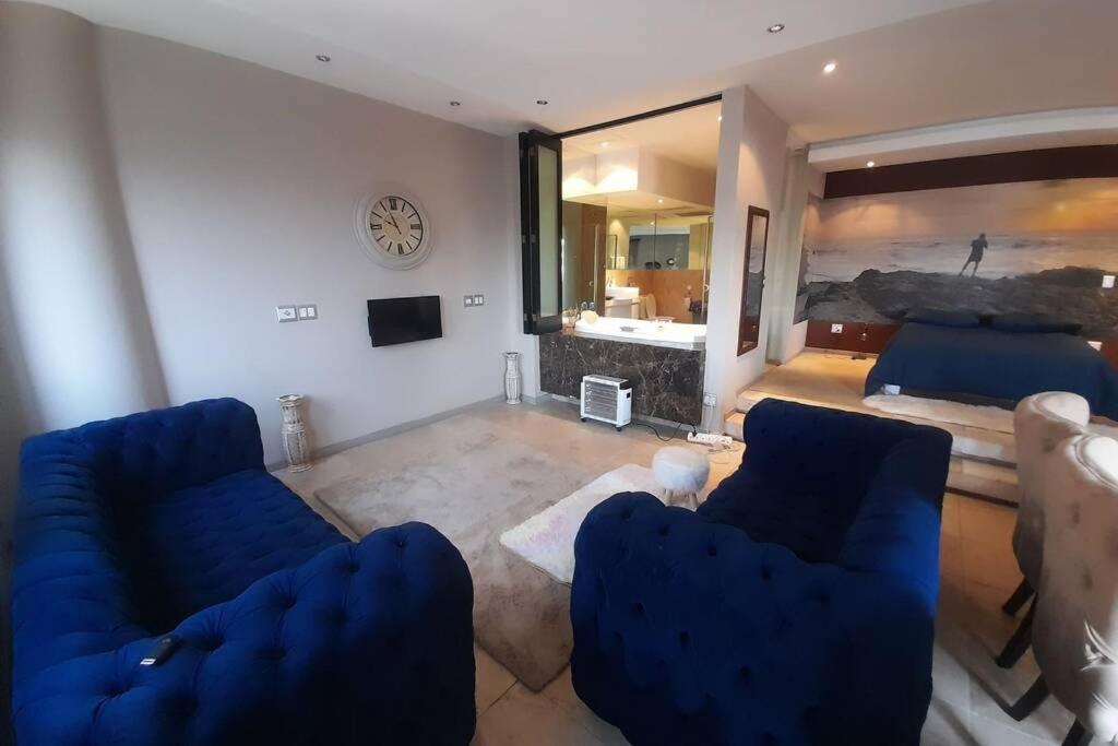 a living room with two blue couches and a bed at Exquisite Apartment with Jaccuzzi Pool Table and Cinema in Johannesburg