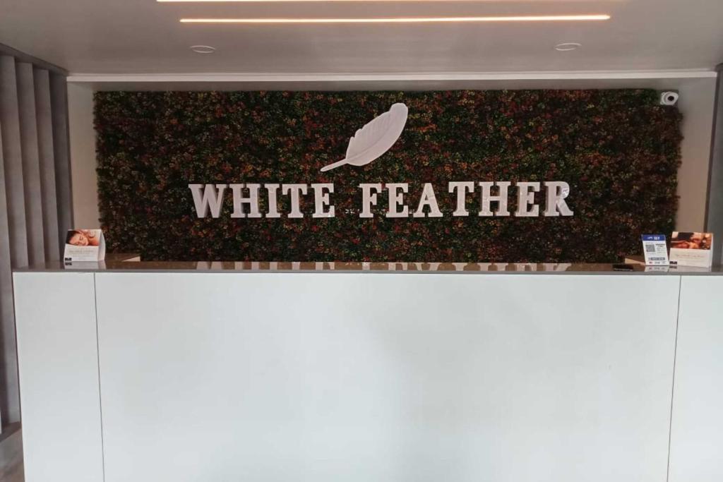 a white feather sign on a wall in a store at White Feather Resort Kauncha in Silvassa