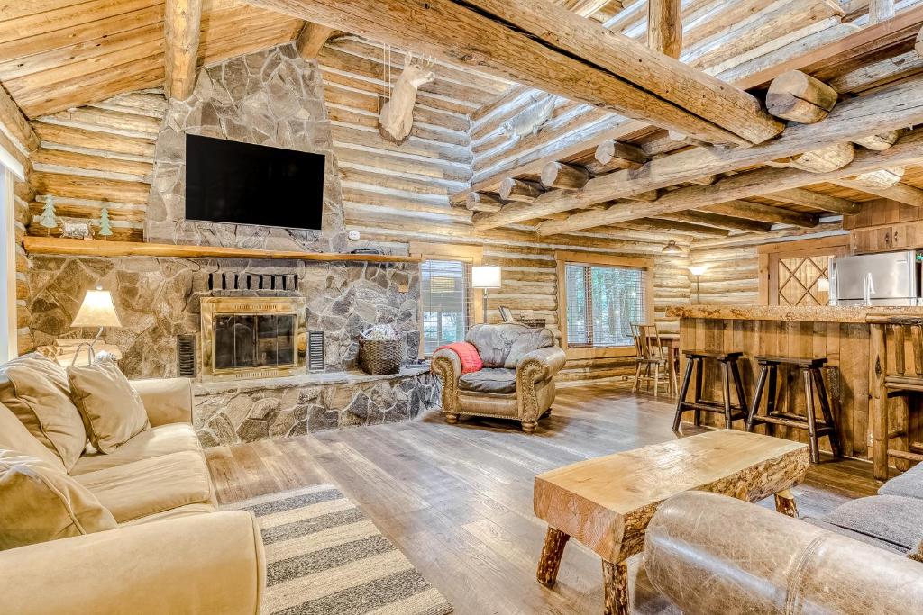 a living room with a stone fireplace and a tv at Best Log Cabin in Brightwood