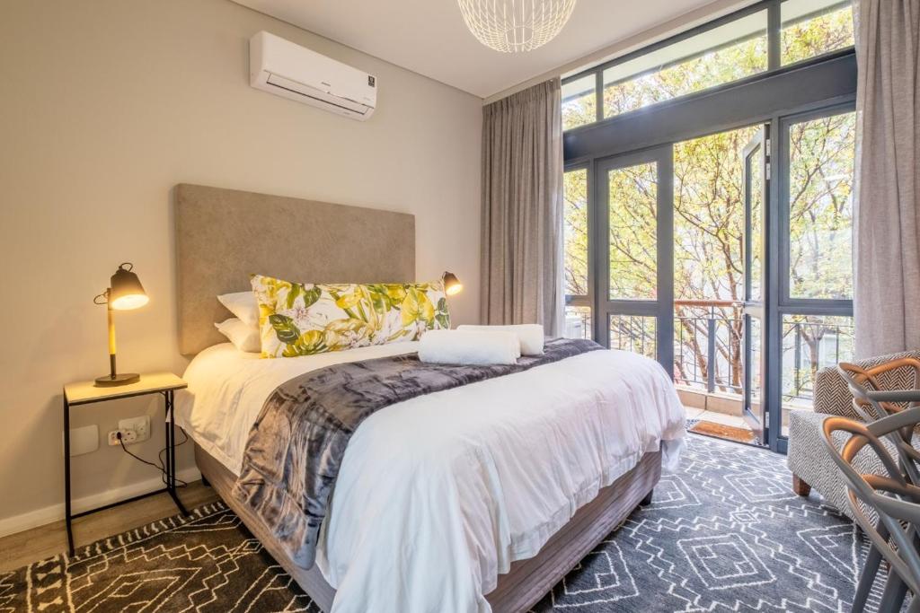 a bedroom with a bed and a large window at Lemon Rind - 16 Eikehoff in Stellenbosch