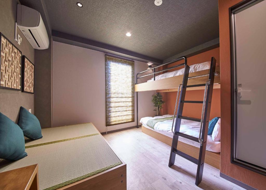 a bedroom with bunk beds and a desk and a ladder at IKIDANE Residential Hotel Sumida Kyojima in Tokyo