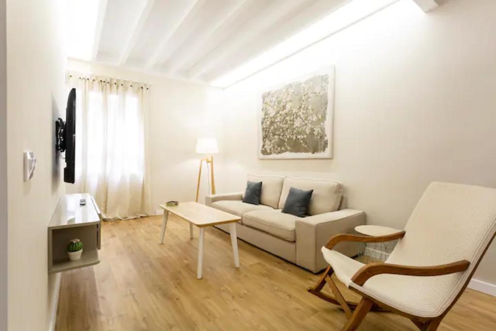 Cream homes La Rambla, TURISMO DE INTERIOR في بالما دي ميورقة: غرفة معيشة بيضاء مع أريكة وطاولة