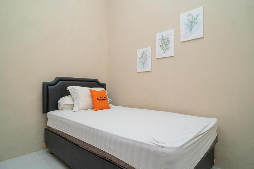 Dormitorio con cama con almohada naranja en Koolkost Syariah near Jalan Ahmad Yani Banjarmasin, en Sungai Lutus