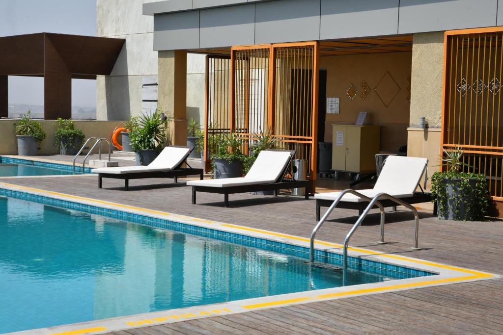 uma piscina com espreguiçadeiras ao lado de um edifício em Grand Mercure Ahmedabad GIFT City - An Accor Hotels Brand em Gandhinagar