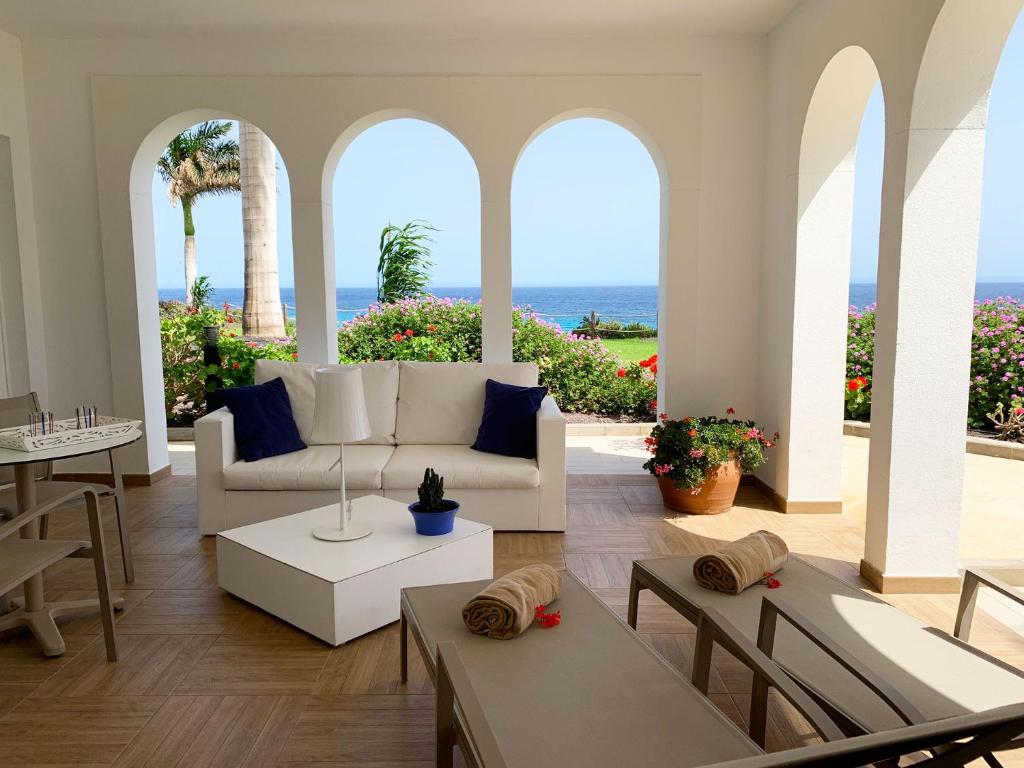a living room with a couch and tables and the ocean at Royal Palm Resort & Spa - Adults Only in Playa Jandia