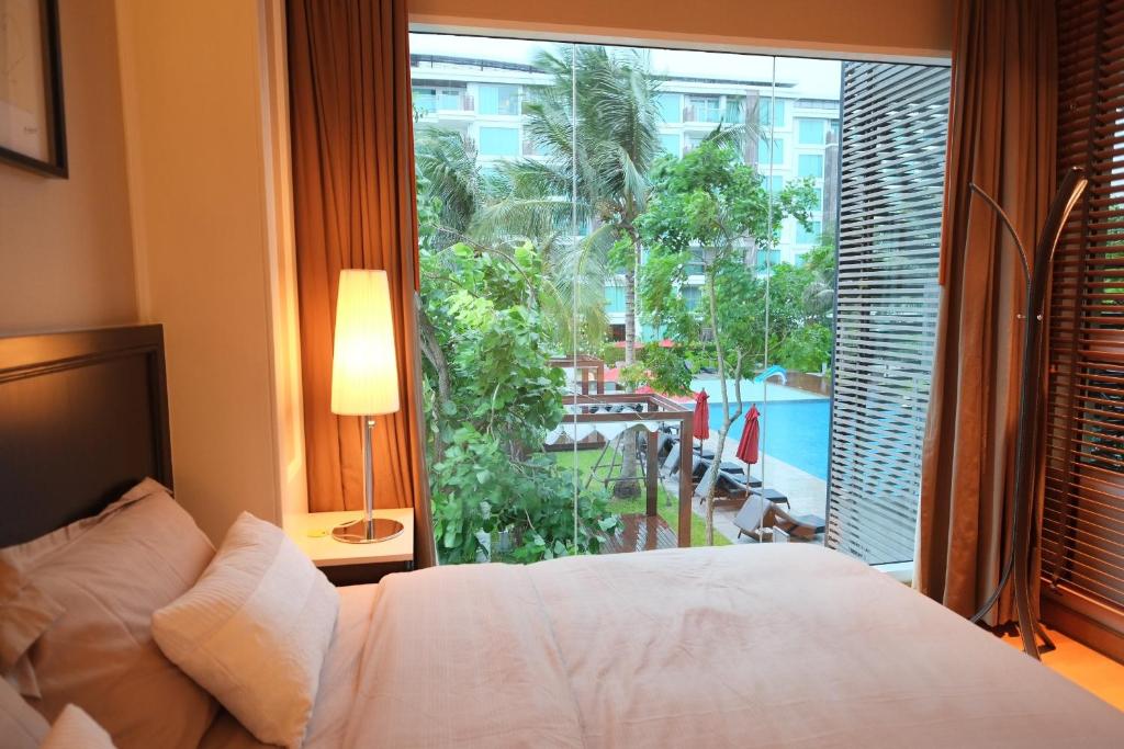a bedroom with a bed and a large window at Amaraze Hua Hin 1 Bedroom Pool View in Hua Hin