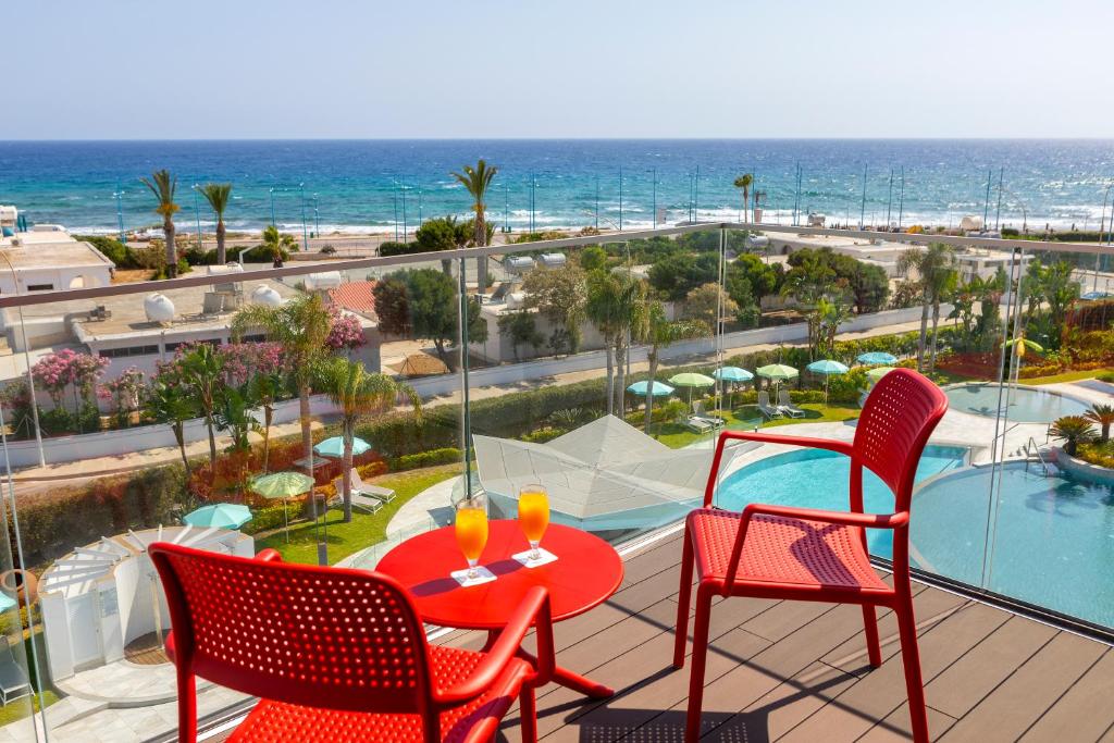 a balcony with a table and chairs and the ocean at Faros Hotel Ayia Napa in Ayia Napa