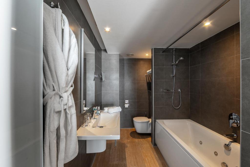 a bathroom with a tub and a sink and a toilet at Faros Hotel Ayia Napa in Ayia Napa