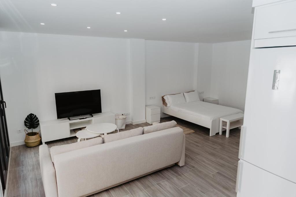 a white living room with a couch and a tv at Charming loft next to wonders of Cordoba in Córdoba