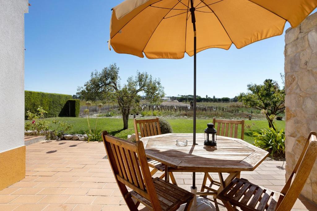 a wooden table with an umbrella on a patio at Monte do Tanoeiro - Casa Tonel in Rogil