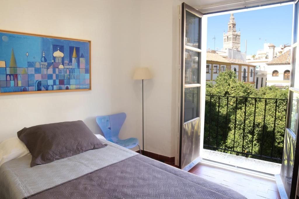 een slaapkamer met een bed en een groot raam bij Apartamentos en la Plaza Doña Elvira, 7 in Sevilla