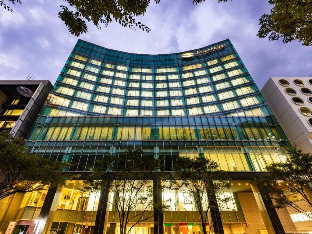 um edifício de vidro alto com árvores em frente em Tenza Hotel at Hakata Station em Fukuoka