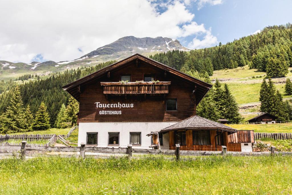 a building in a field next to a mountain at Gästehaus Tauernhaus in Matrei in Osttirol