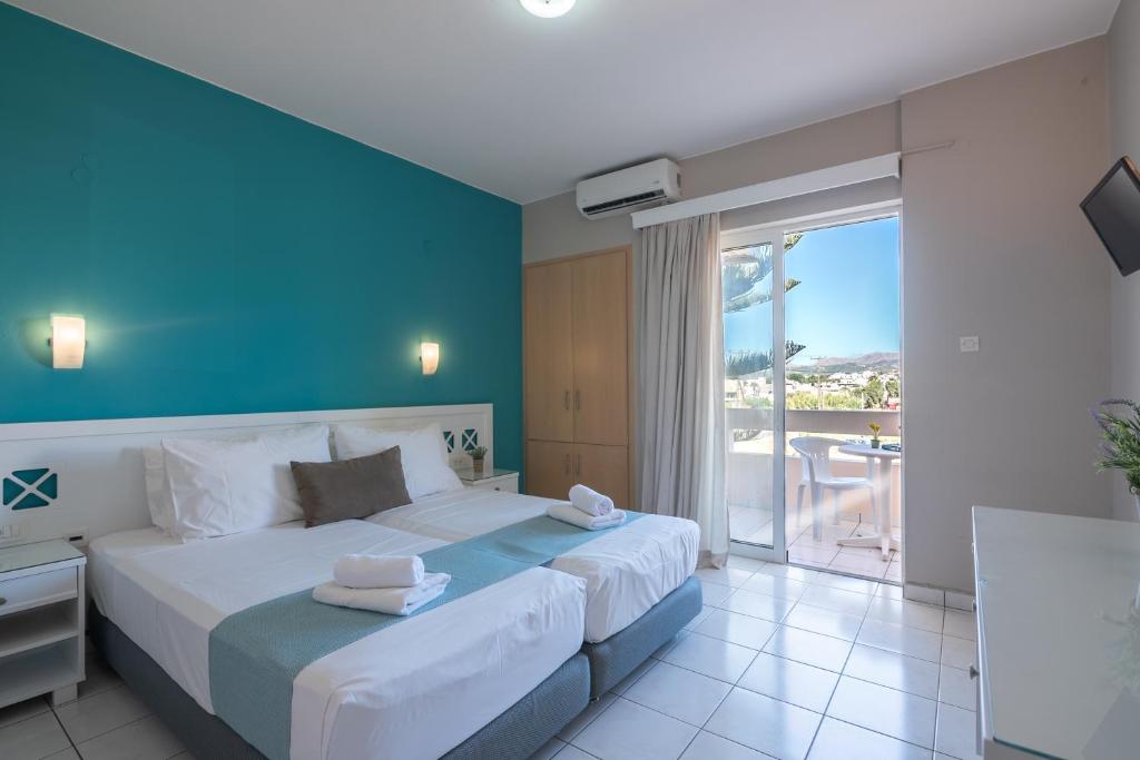 a bedroom with a large bed with a blue wall at Hermes Hotel in Kissamos